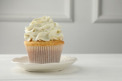 Photo of Tasty vanilla cupcake with cream on white table, closeup. Space for text