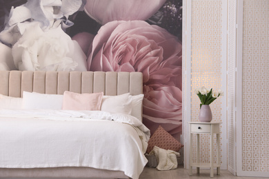 Photo of Beautiful room interior with large comfortable bed and floral pattern on wall