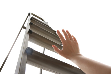 Woman climbing up stepladder on white background, low angle view