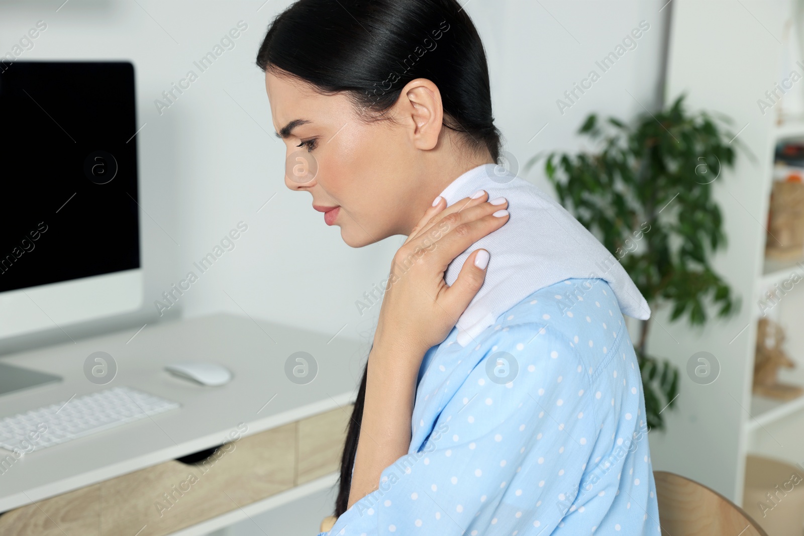 Photo of Young woman using heating pad at home