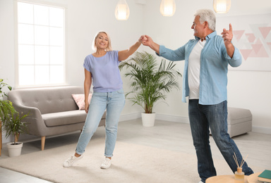 Happy mature couple dancing together in living room