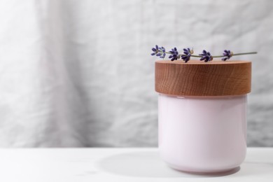 Photo of Jar of hand cream and lavender on white table, space for text