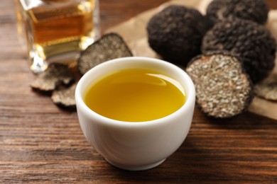 Photo of Fresh truffle oil in bowl on wooden table, closeup