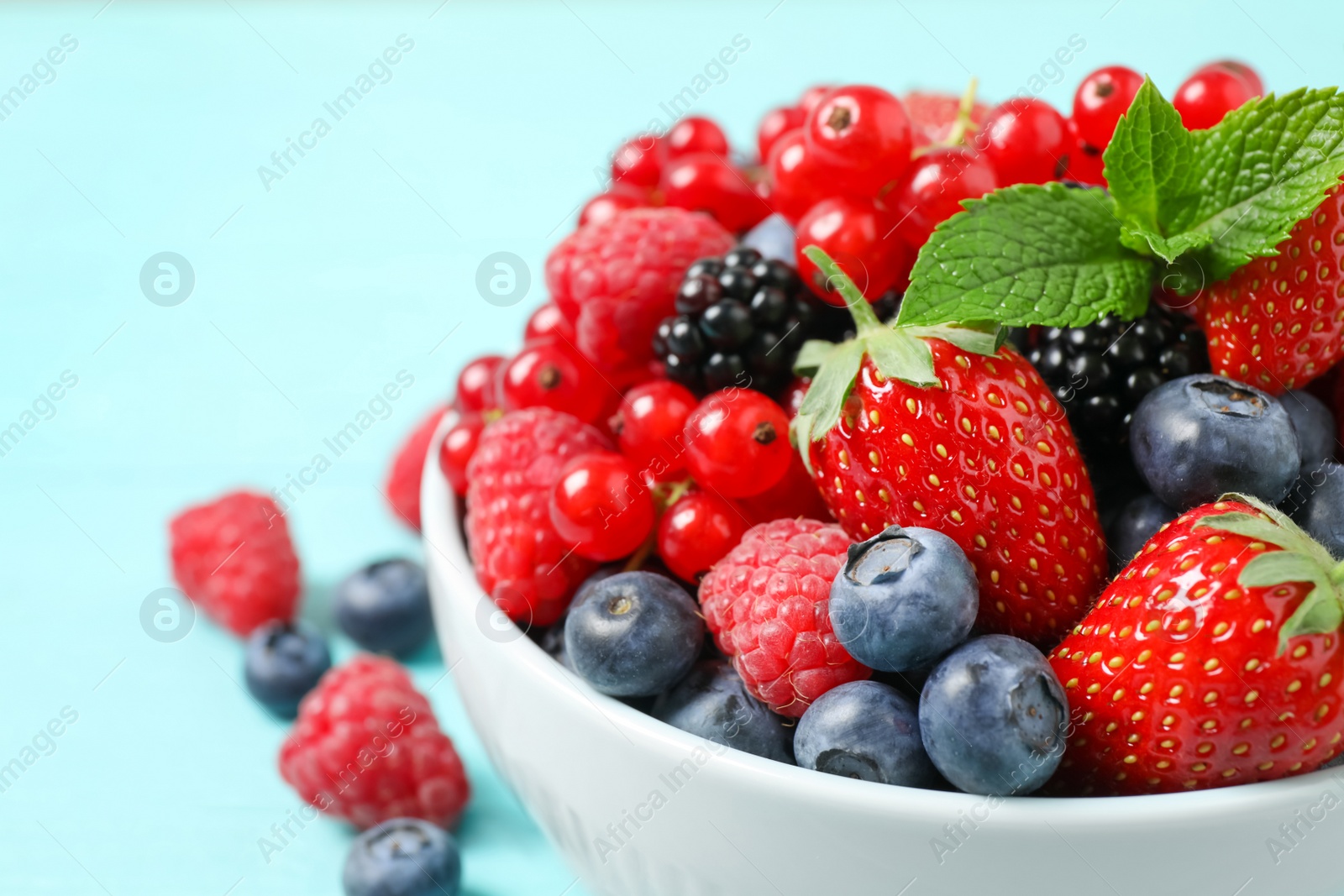 Photo of Mix of different fresh berries and mint in bowl on table, closeup