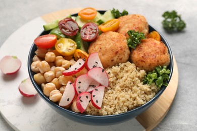 Photo of Delicious vegan bowl with chickpeas, cutlets and radish on grey table, closeup