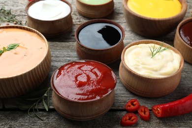 Photo of Many bowls with different sauces on wooden table