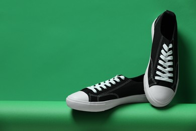 Photo of Pair of stylish sneakers on green background, space for text