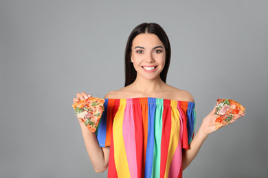 Beautiful woman with pizza on grey background