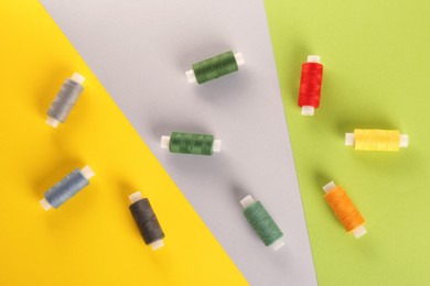 Photo of Different sewing threads on color background, flat lay