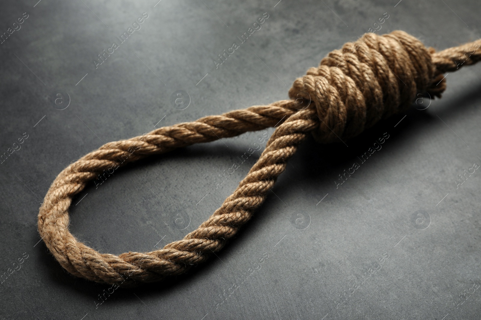 Photo of Rope noose with knot on grey table, closeup