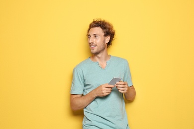 Young man with mobile phone on color background