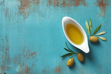 Gravy boat with oil, olives and leaves on wooden table, top view