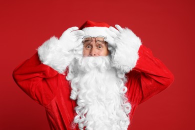 Photo of Merry Christmas. Surprised Santa Claus on red background