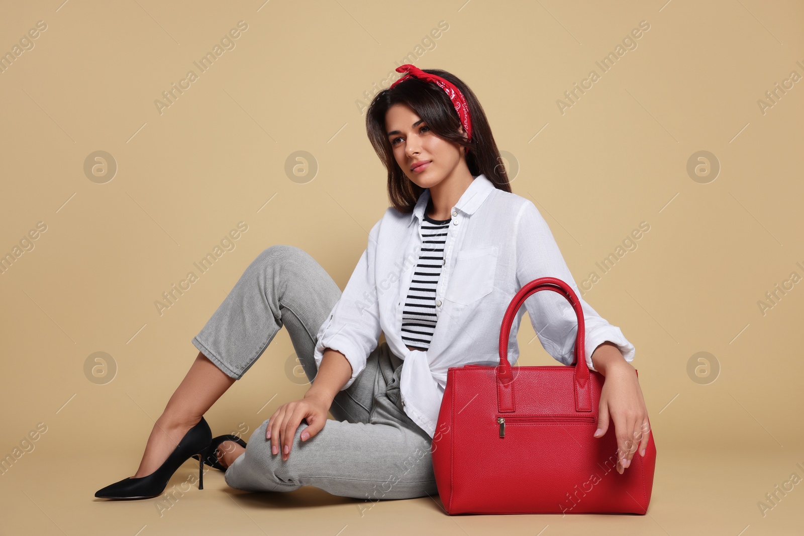 Photo of Young woman with stylish bag on beige background