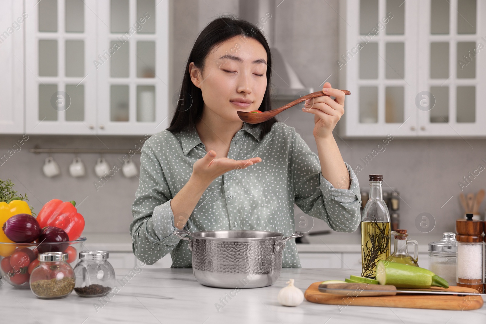 Photo of Beautiful woman tasting food after cooking in kitchen