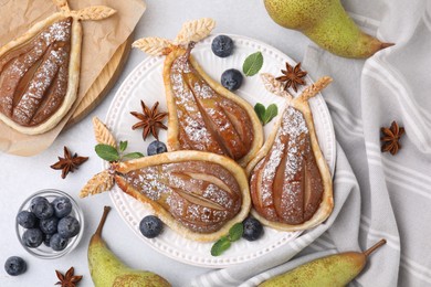 Photo of Delicious pears baked in puff pastry with powdered sugar served on light grey table, flat lay