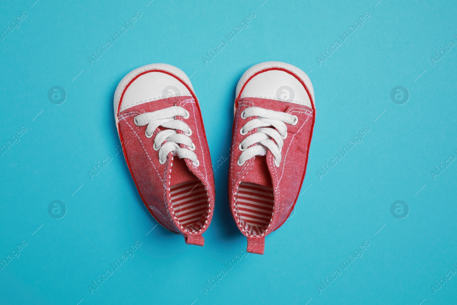 Photo of Cute baby shoes on light blue background, flat lay