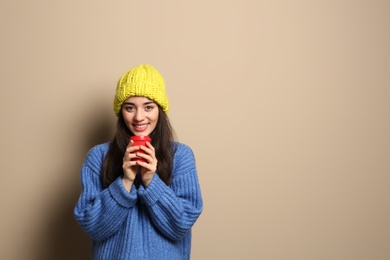 Photo of Young woman in sweater with cup of hot coffee on color background, space for text. Winter season