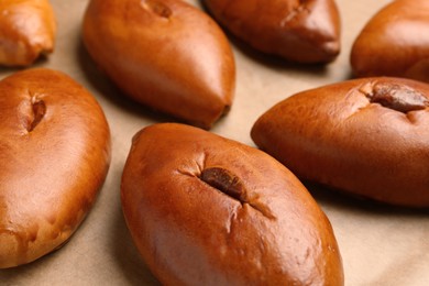 Photo of Many delicious baked patties on parchment paper, closeup