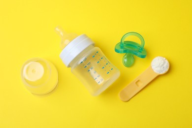 Flat lay composition with powdered infant formula on yellow background. Baby milk