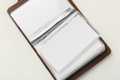 Leather business card holder with blank cards on white table, top view