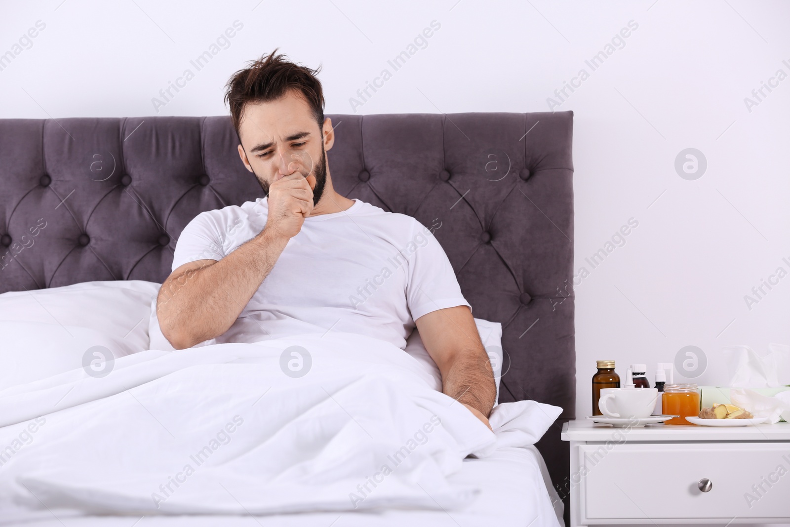 Photo of Ill man suffering from cough in bed at home