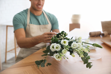 Photo of Florist making beautiful bouquet at table in workshop, closeup