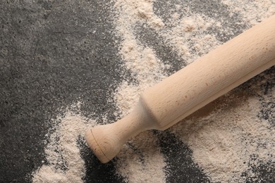 Photo of Scattered flour and rolling pin on grey textured table, top view