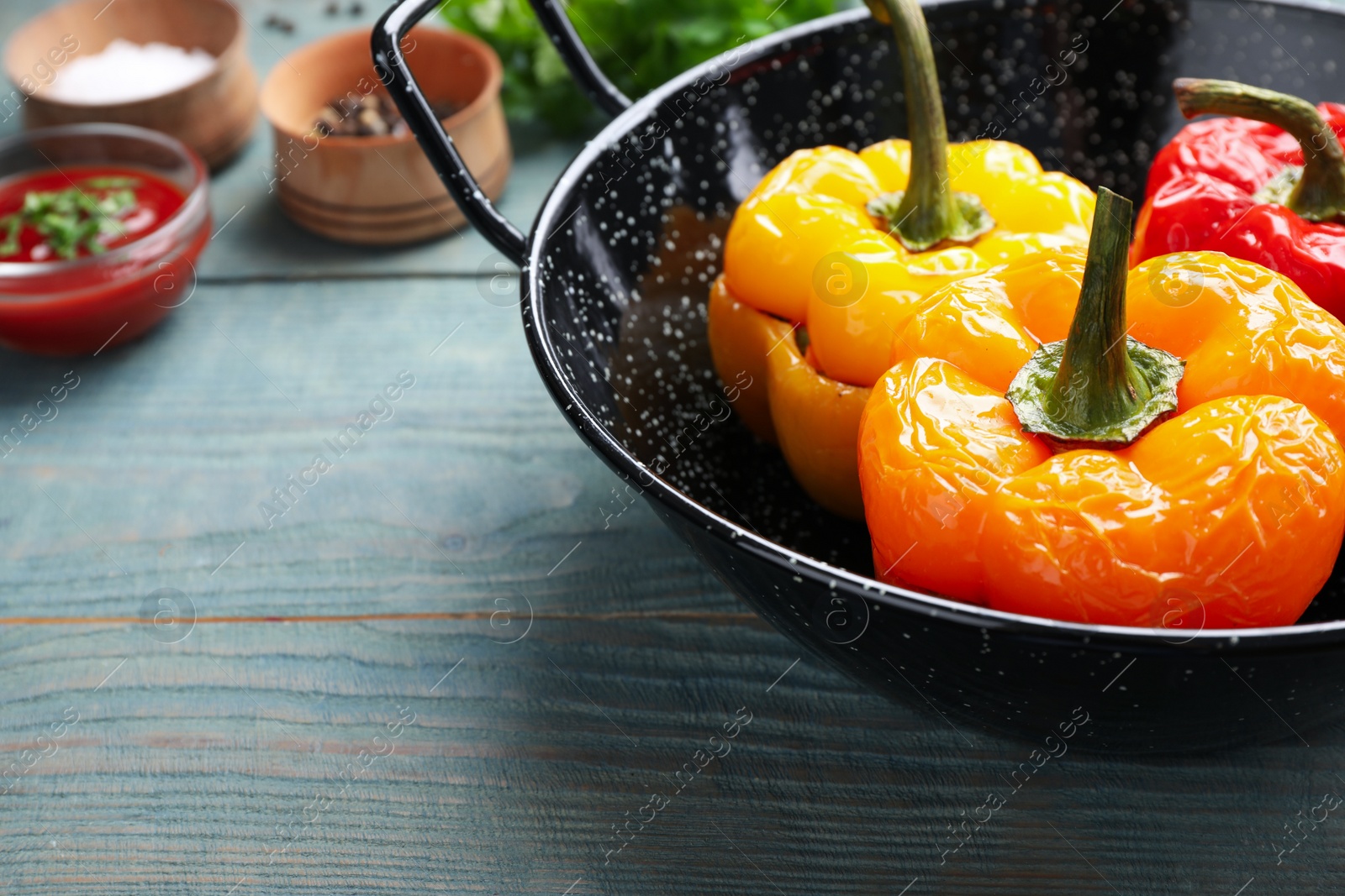 Photo of Tasty stuffed bell peppers in baking dish on blue wooden table, closeup