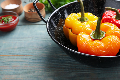 Photo of Tasty stuffed bell peppers in baking dish on blue wooden table, closeup