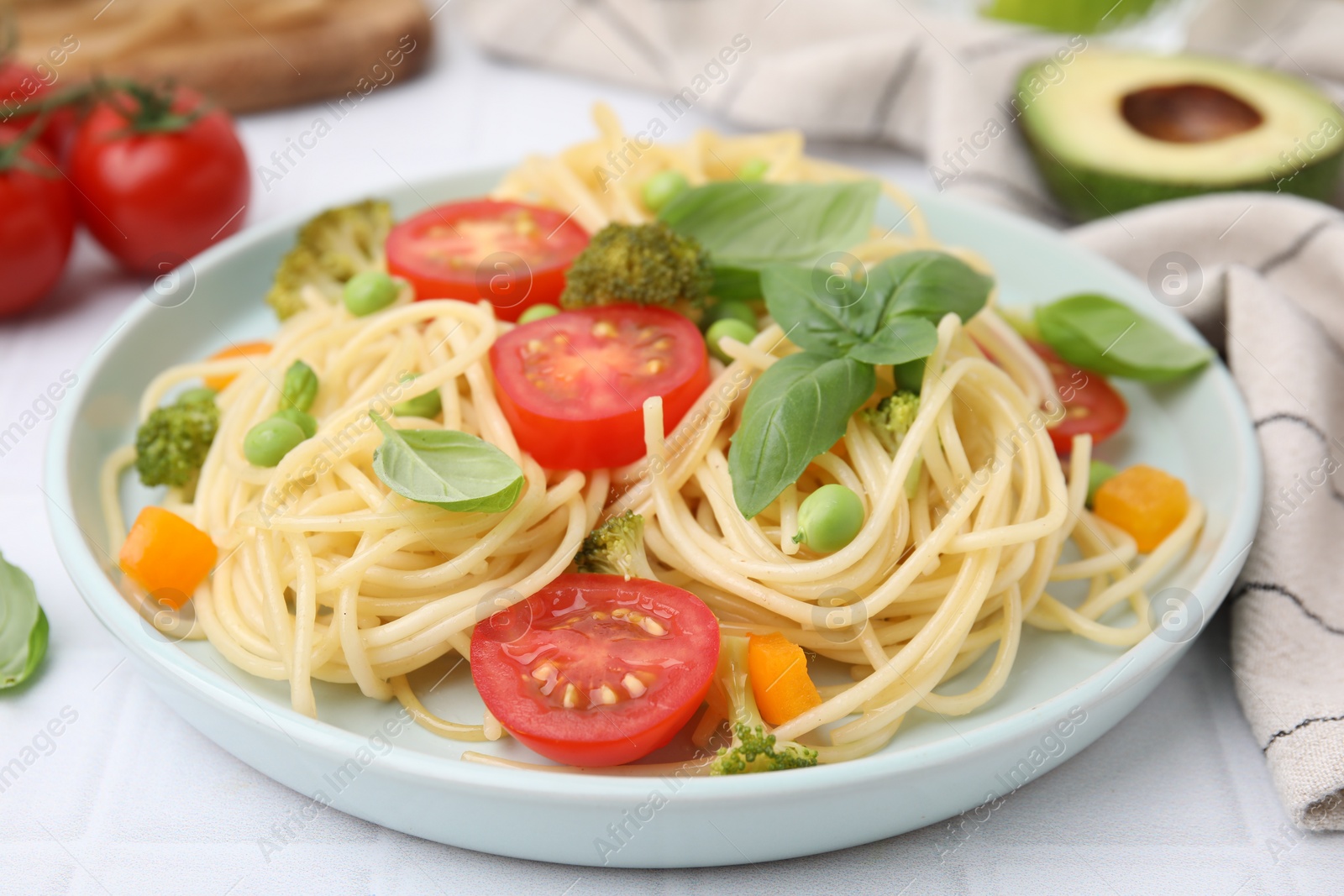 Photo of Plate of delicious pasta primavera and ingredients on white table, closeup