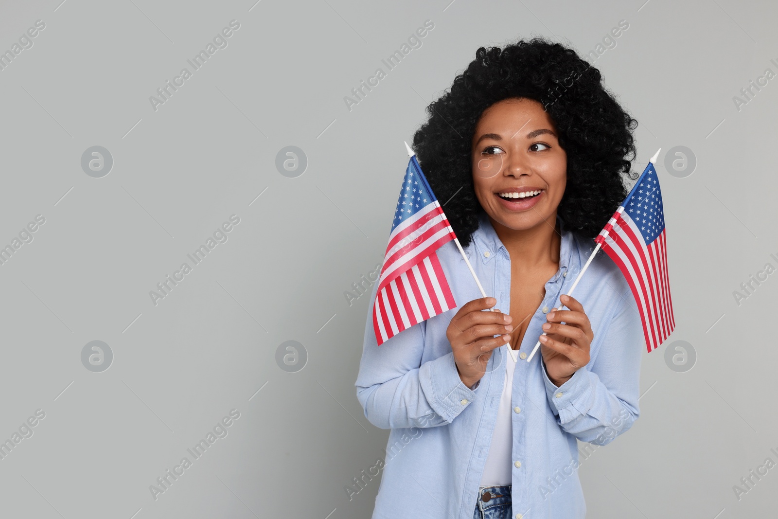 Photo of 4th of July - Independence Day of USA. Happy woman with American flags on light grey background, space for text