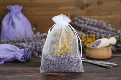 Photo of Scented sachet with dried flowers on wooden table