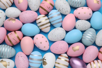 Many painted Easter eggs on blue background, flat lay