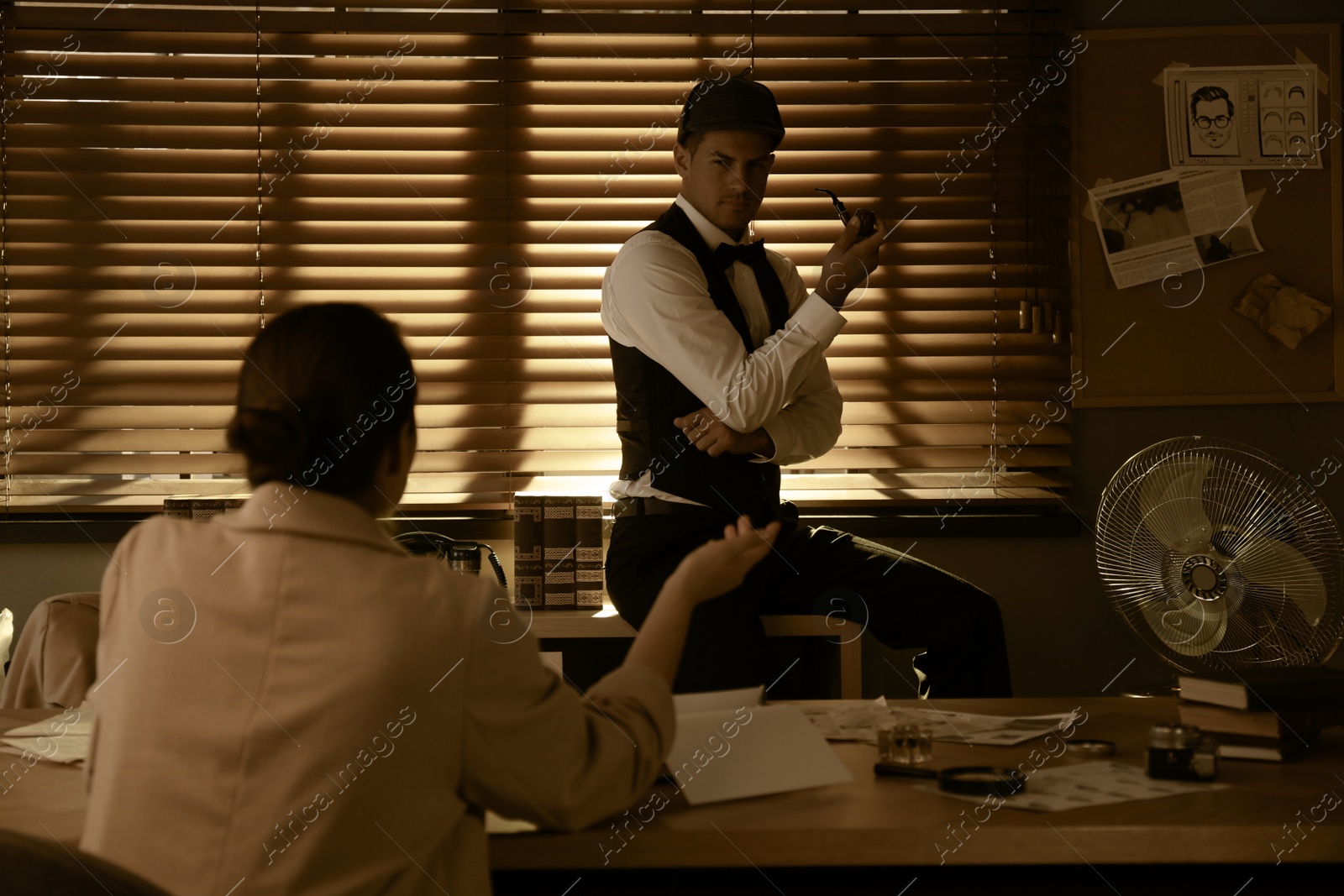 Photo of Old fashioned detective working with client in office