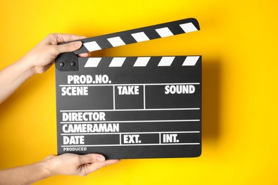 Photo of Woman holding clapperboard on color background, closeup. Cinema production