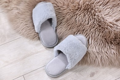 Photo of Grey soft slippers on light wooden floor at home, above view