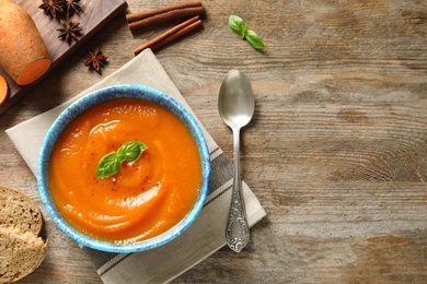 Bowl of tasty sweet potato soup served on table, top view. Space for text