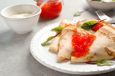 Thin pancakes served with red caviar on plate