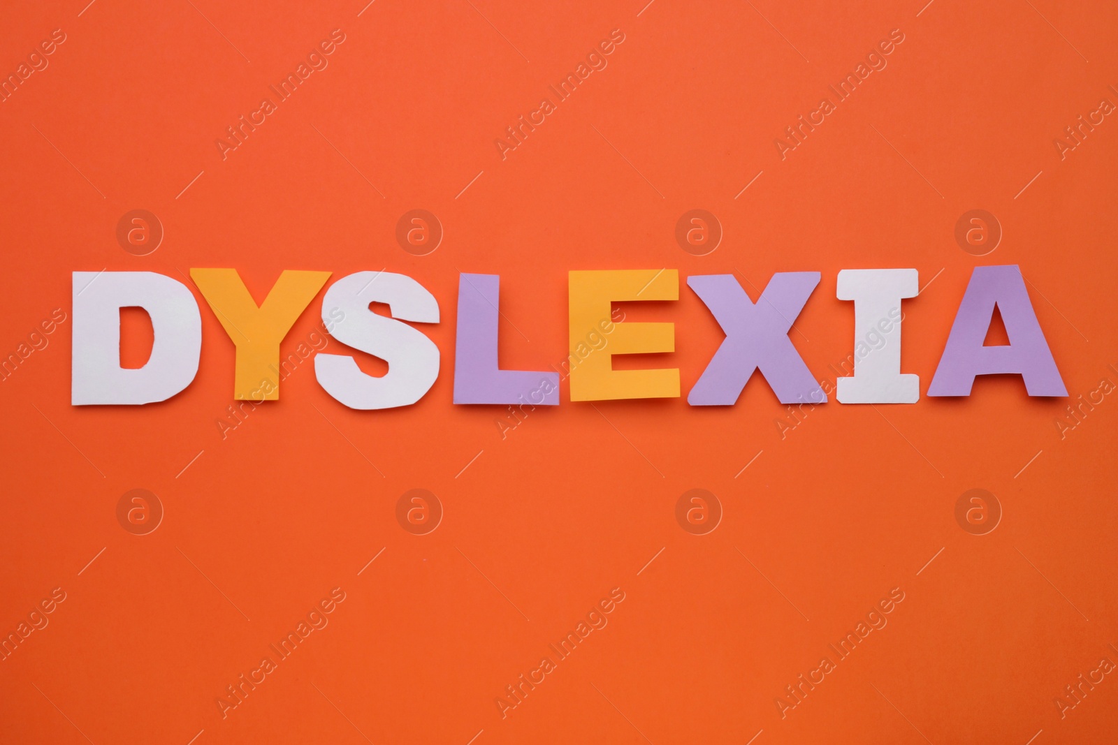 Photo of Word Dyslexia made of paper letters on orange background, flat lay