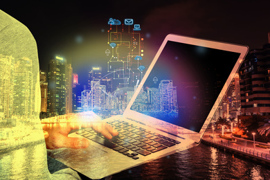 Image of Young man with laptop and virtual image of city, closeup. Modern technology