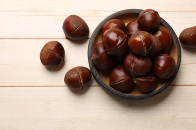 Photo of Roasted edible sweet chestnuts on wooden table, flat lay