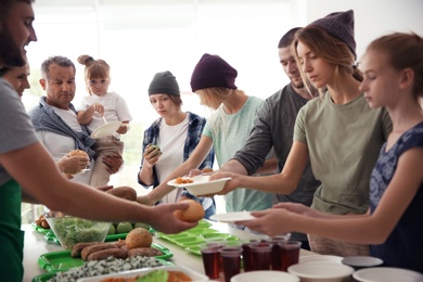 Photo of Volunteers serving food for poor people indoors