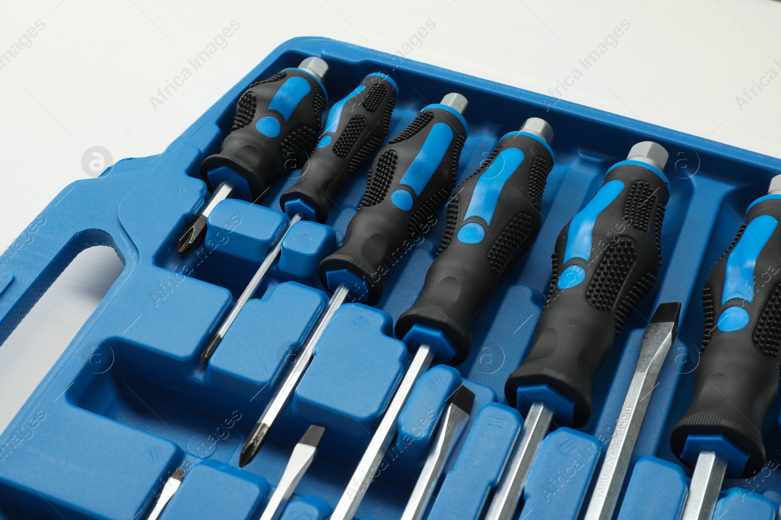 Photo of Set of screwdrivers in open toolbox on white wooden table, closeup