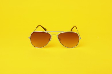 Stylish pair of sunglasses on yellow background