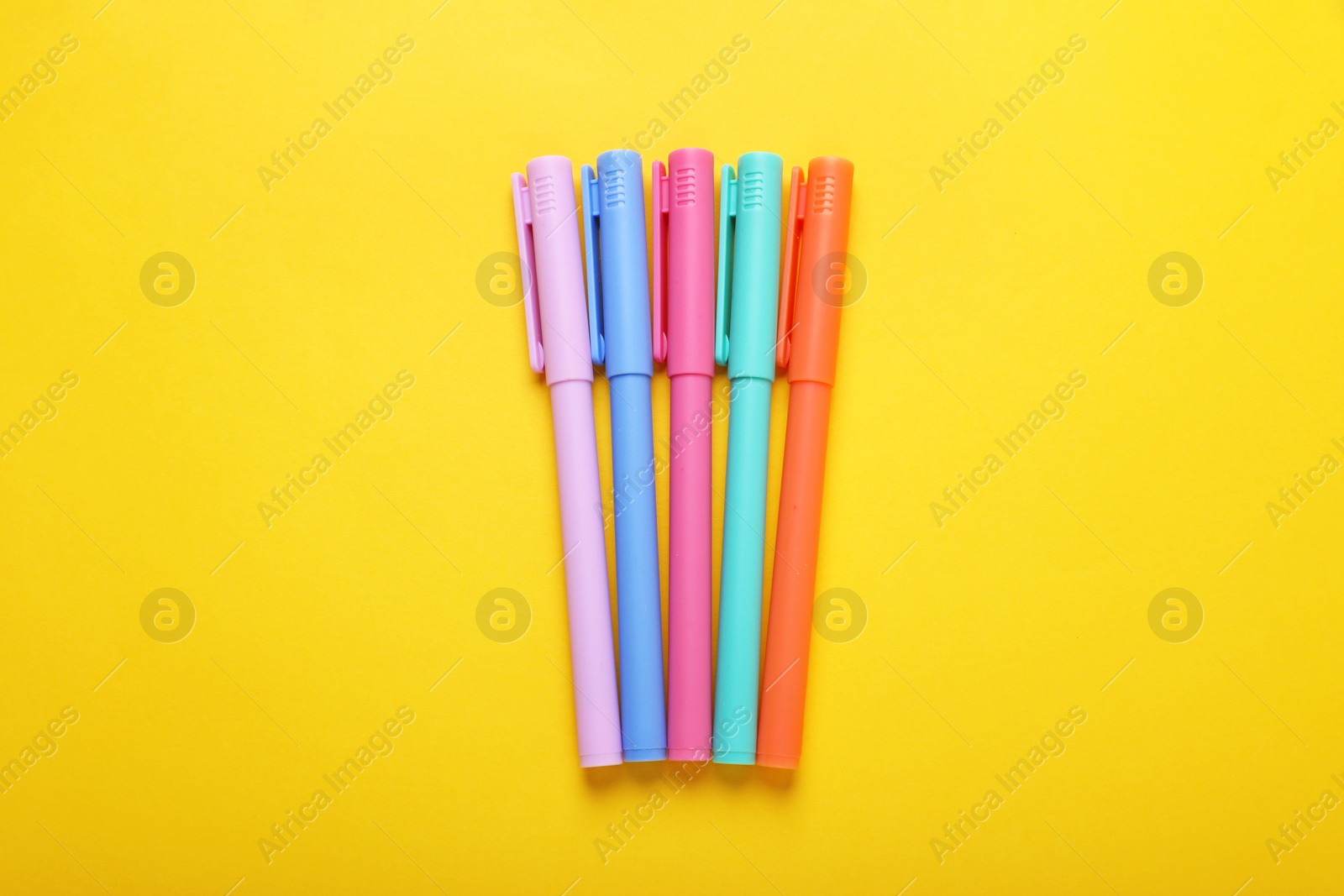 Photo of Many colorful markers on yellow background, flat lay