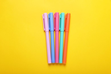 Photo of Many colorful markers on yellow background, flat lay
