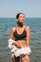 Beautiful young woman in stylish bikini near sea