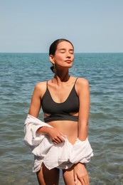 Photo of Beautiful young woman in stylish bikini near sea