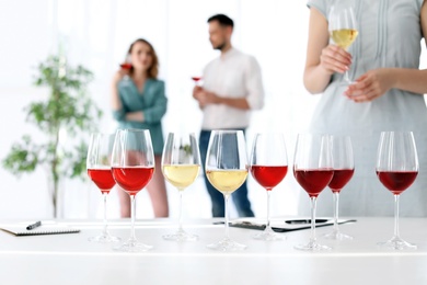 Photo of Glasses with delicious wine and blurred people on background